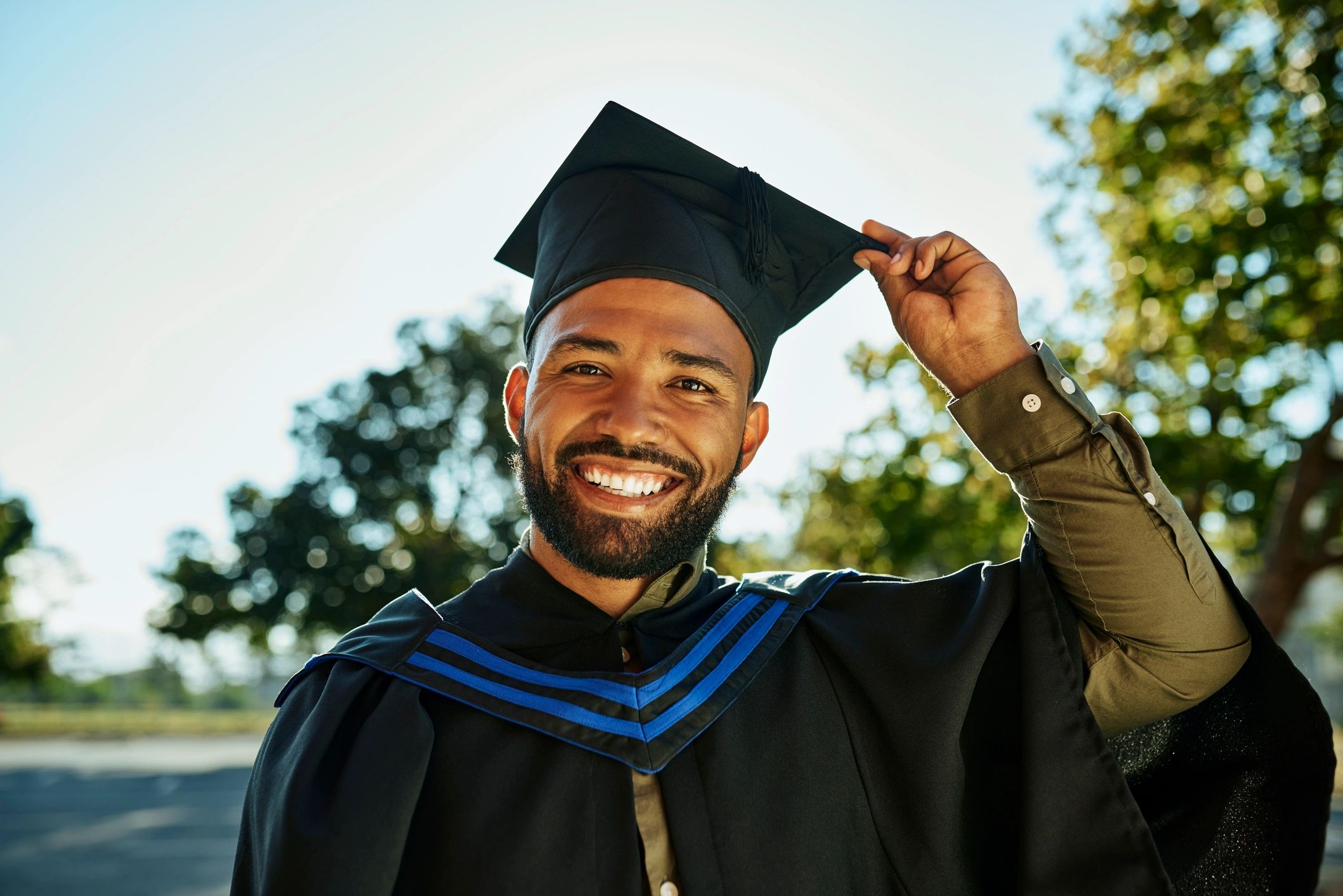 Smiling graduate in cap and gown on campus