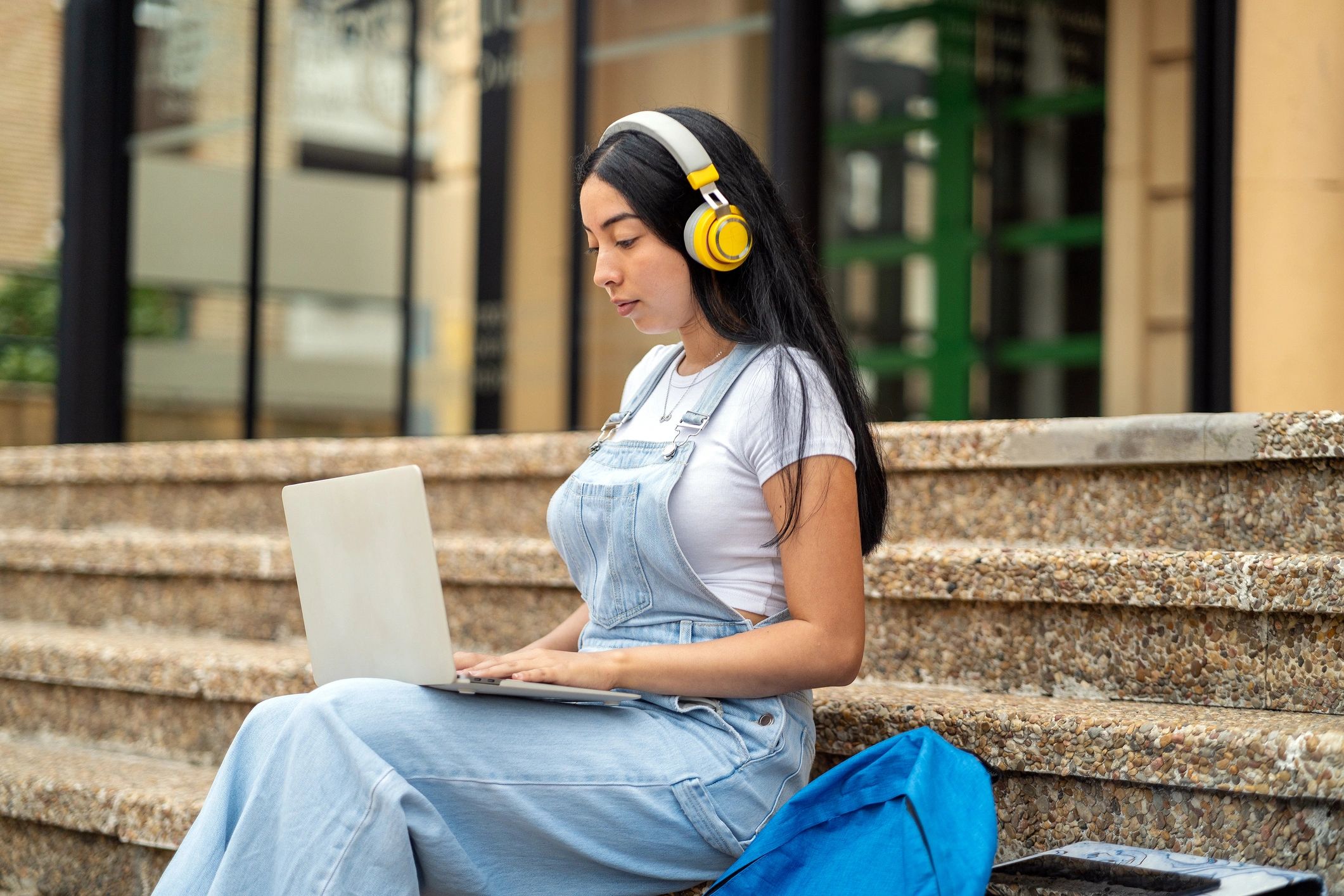 Student working on a laptop on campus steps
