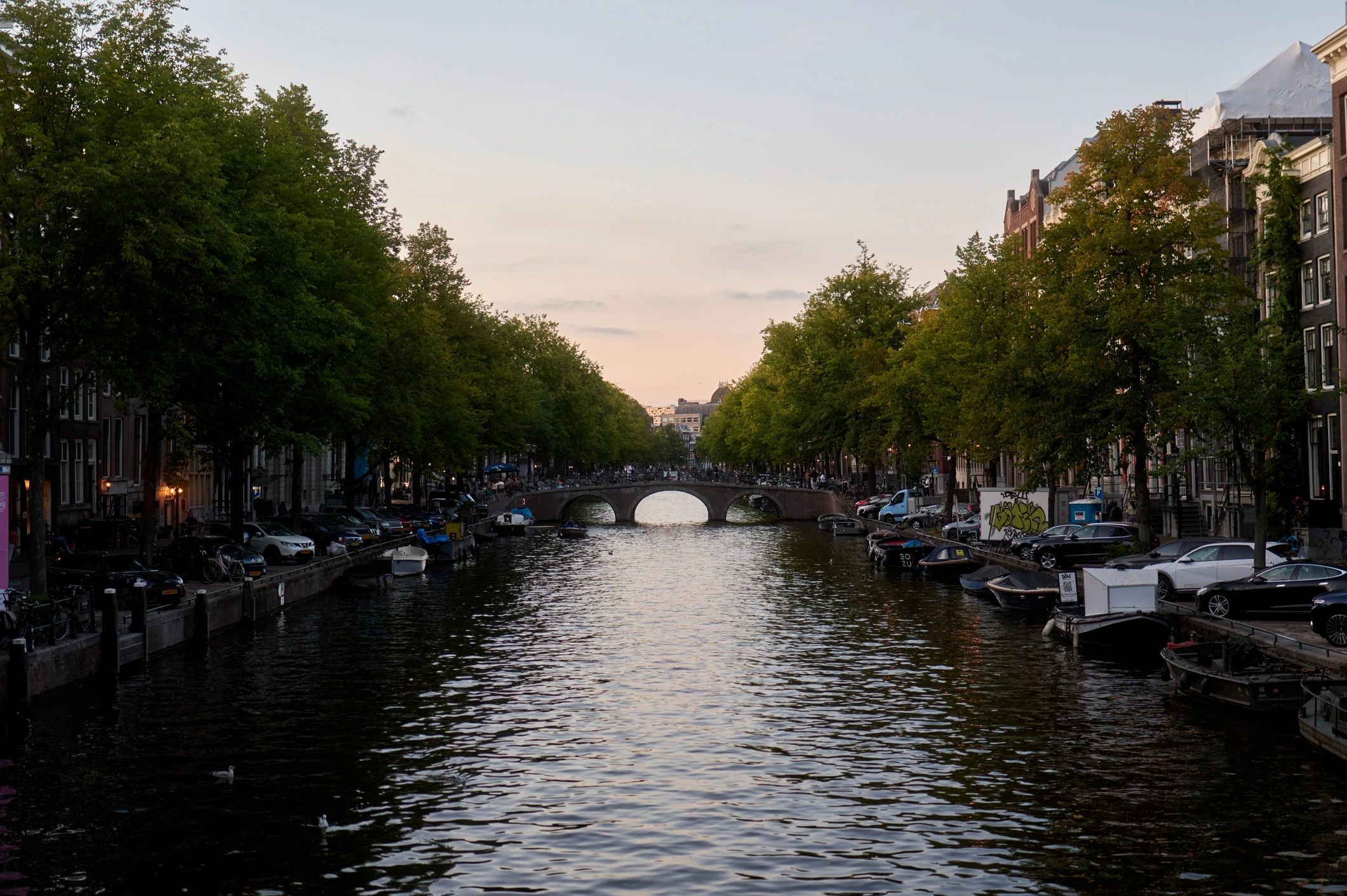 Amsterdam canal at dusk with bridge and boats